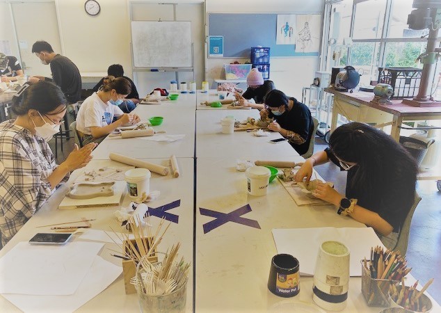 Students sitting around a table working on ceramics