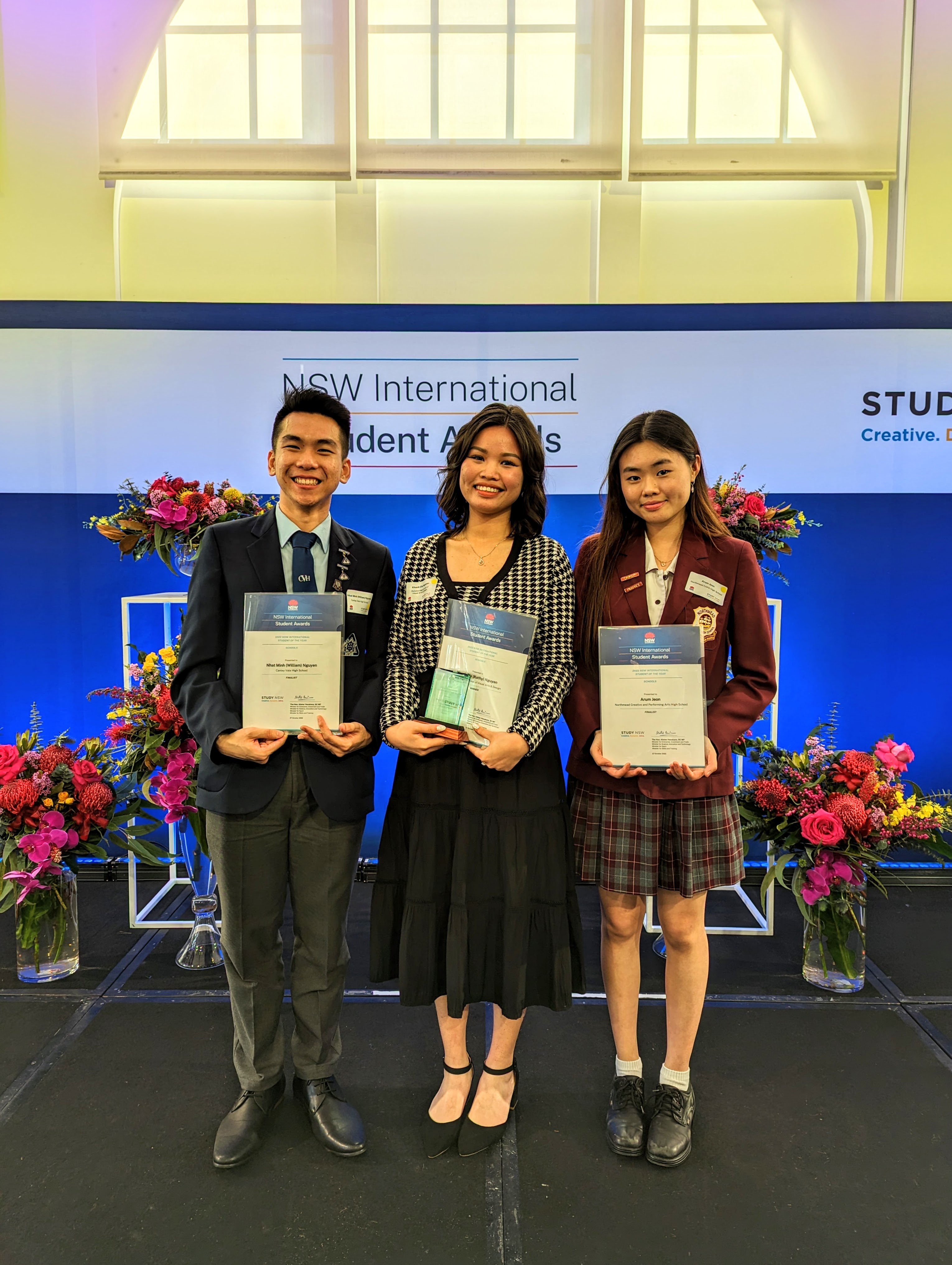 three students with certificates and trophies