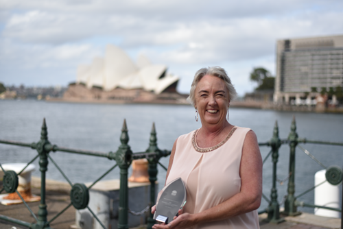 female with and award in front of the Sydney Opera House